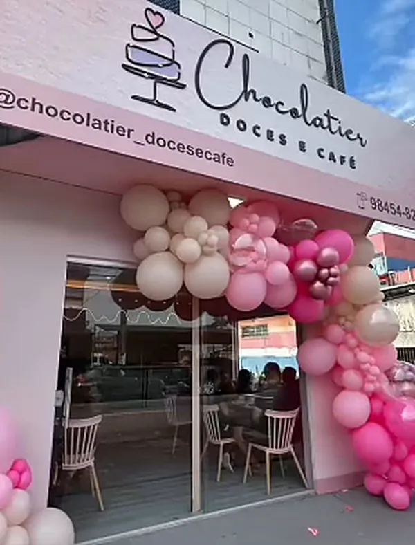 Fachada rosa com o letreiro Chocolatier Doces e Café e arco de balões